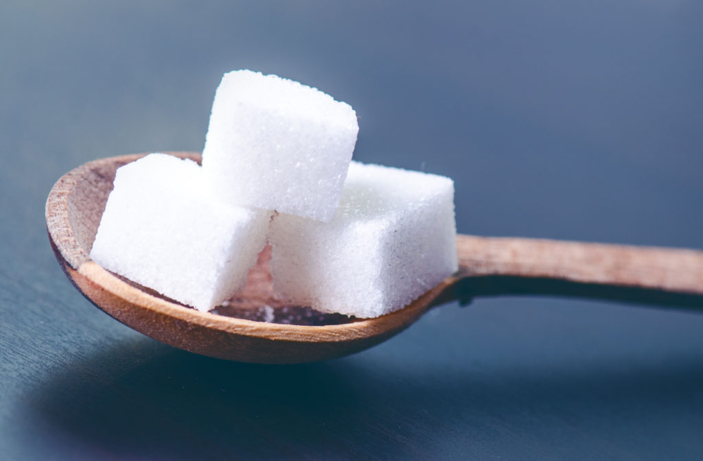 A close-up of sugar cubes on a wooded spoon.