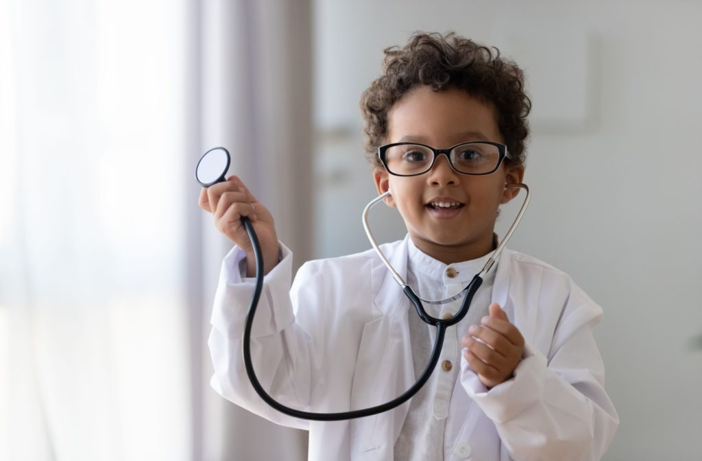 A young boy wearing doctor costume with an oversized lab coat, stethoscope, and glasses.