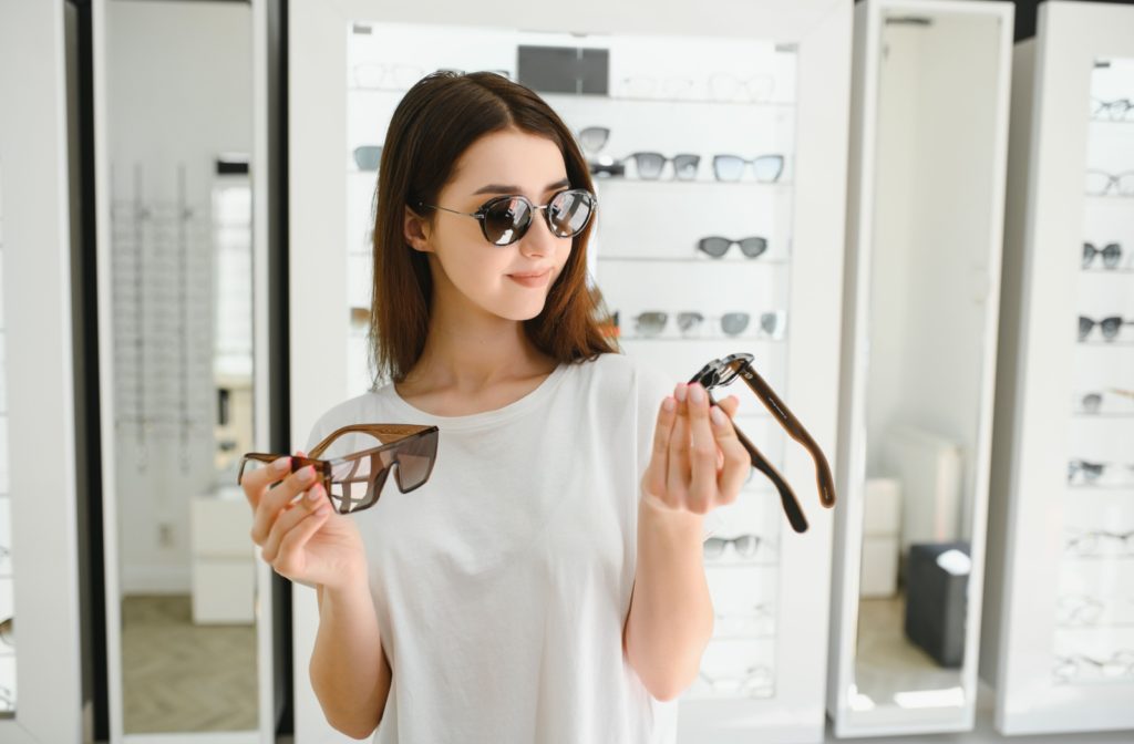 A woman trying on various sunglasses in the eye doctor's clinic.