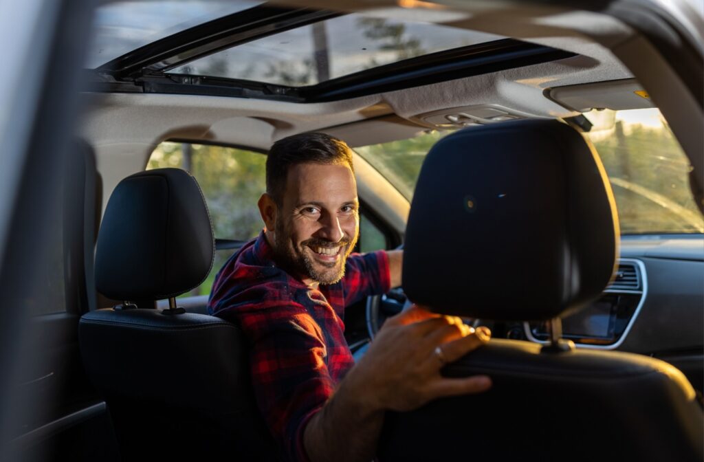 A person in the driver's seat turns around and smiles, facing the back of the car.