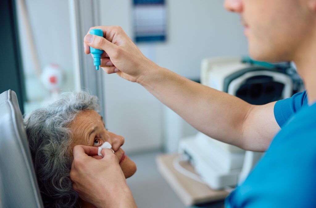 An optometrist carefully administers dilating eye drops to a patient.
