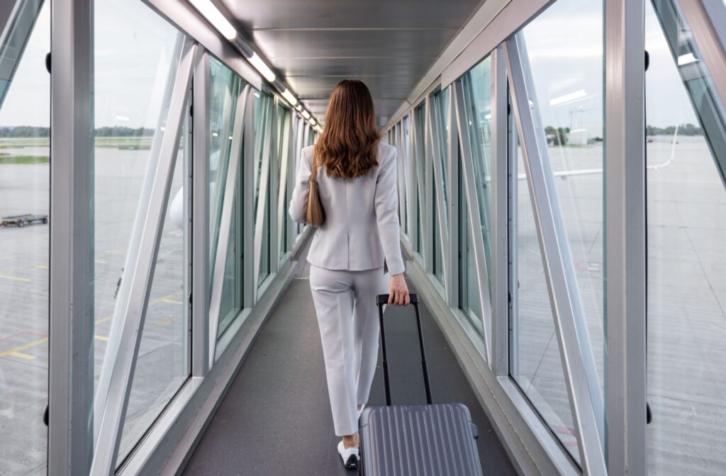 A person walking to board a plane with carry on luggage